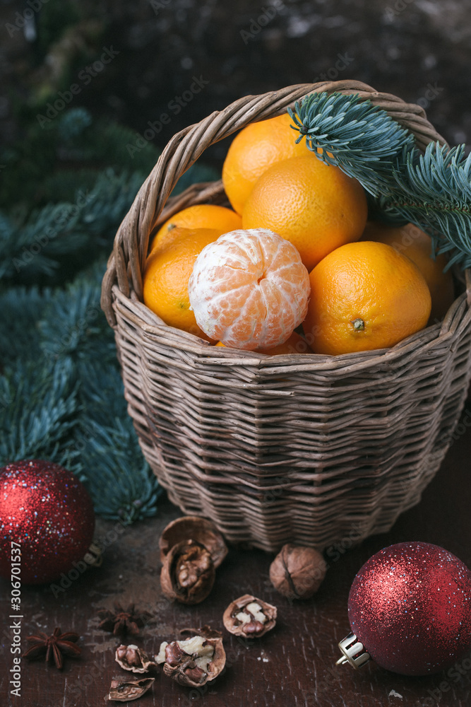Holiday content, tangerines, peeled tangerine in a wicker basket, vintage, spruce branch, Christmas tree red balls, walnut, dark brown background