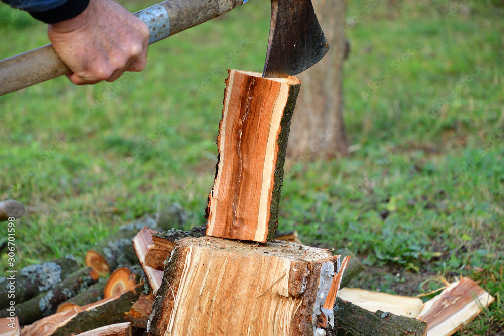 Splitting wood with an ax into smaller logs in traditional way Splitting wood with an ax into smaller logs in traditional way
