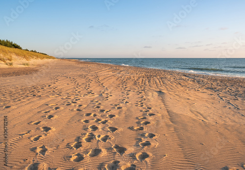 wild beach coastline with footprints. evening lights