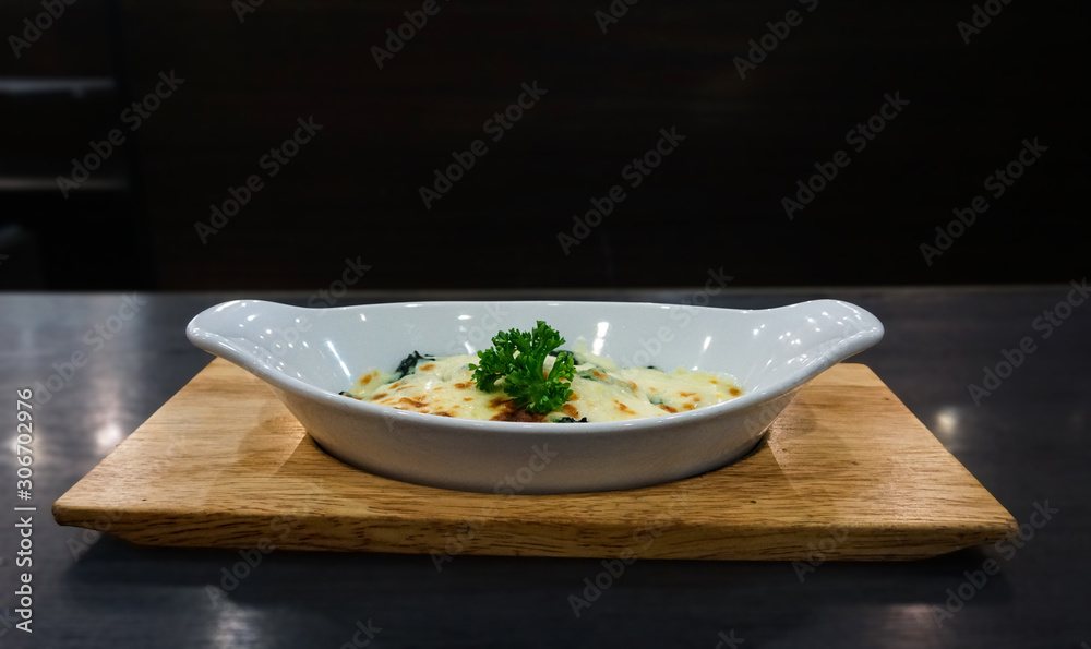 Baked spinach and cheese in a white cup ready The wooden table on the background Baked spinach and cheese in a white cup ready The wooden table on the background