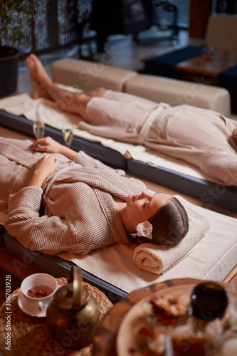 Drinking tea and relaxing in spa salon, lying down on beds and enjoy wearing bathrobe