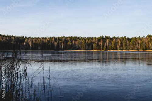 Landscape of the earthly partly frozen lake. The lake begins to become covered with ice. Great place for winter ice fishing on the lake.