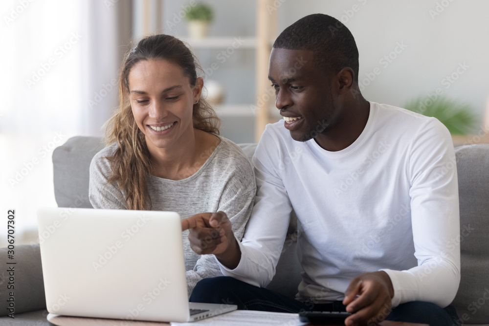 Happy mixed race family spouse making monthly budget calculations. Happy mixed race family spouse making monthly budget calculations.