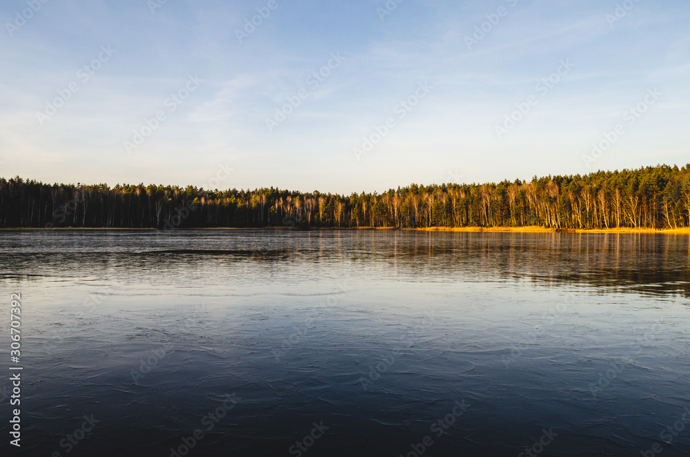 Winter landscape on a lake covered with ice without snow. At sunset, the landscape of a frozen lake.