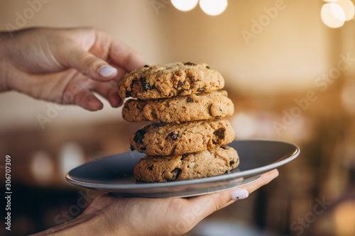 close up photo of delicious and crunchy oatmeal cookies on the backdrop of a cozy restaurant or bakery interior, festive Christmas mood, 4 cookies lying on top of each other