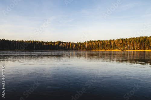 Winter landscape on a lake covered with ice without snow. At sunset  the landscape of a frozen lake.