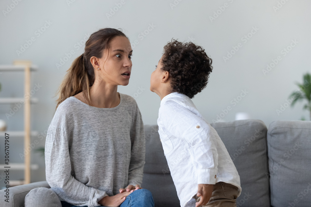 Provocative mixed race little kid demonstrating impolite behavior to mom. Provocative mixed race little kid demonstrating impolite behavior to mom.