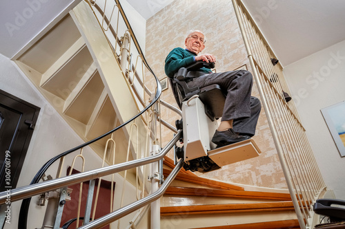 Elderly Man in the Staircase Using the Stairlift photo
