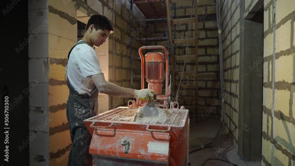 Plastering mortar machine. Automatic plaster. Repairing or renovating house or apartment. Builder at construction professional Plastering mortar machine. Automatic plaster. Repairing or renovating house or apartment. Builder at construction professional