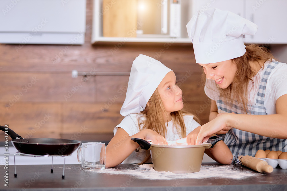 beautiful happy mother and daughter baking together in the kitchen, young woman with helper daughter going to bake delicious tasty cake beautiful happy mother and daughter baking together in the kitchen, young woman with helper daughter going to bake delicious tasty cake