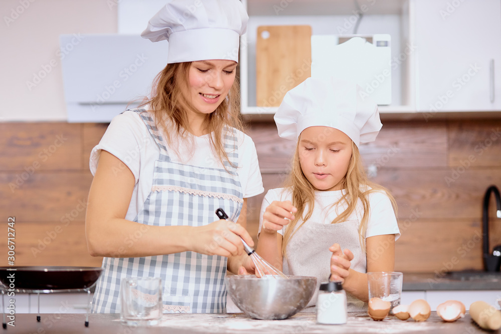 caucasian mother and daughter bake together, make dough and use ingredients need for it. Happy teamwork in kitchen of woman and her child caucasian mother and daughter bake together, make dough and use ingredients need for it. Happy teamwork in kitchen of woman and her child