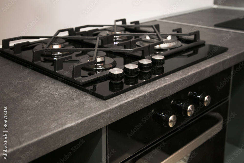 Fragment the stainless cooking plate. The steel gas hob detail on black stone surface. Fragment the stainless cooking plate. The steel gas hob detail on black stone surface.