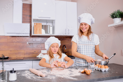 mother and kid girl together in kitchen, baking and cooking together at home , enjoy spending time together, baking delicious cakes