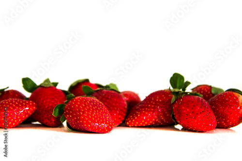Bright red fresh ripe strawberries berries scattered and isolated on a white background