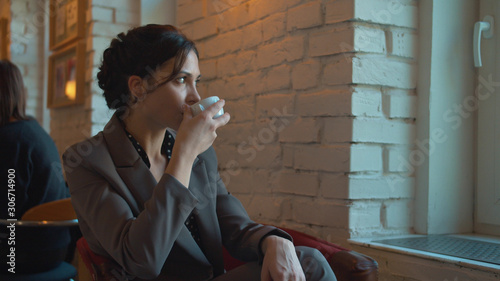 Obraz na plátně Lady drinks coffee and looks out the window reflecting