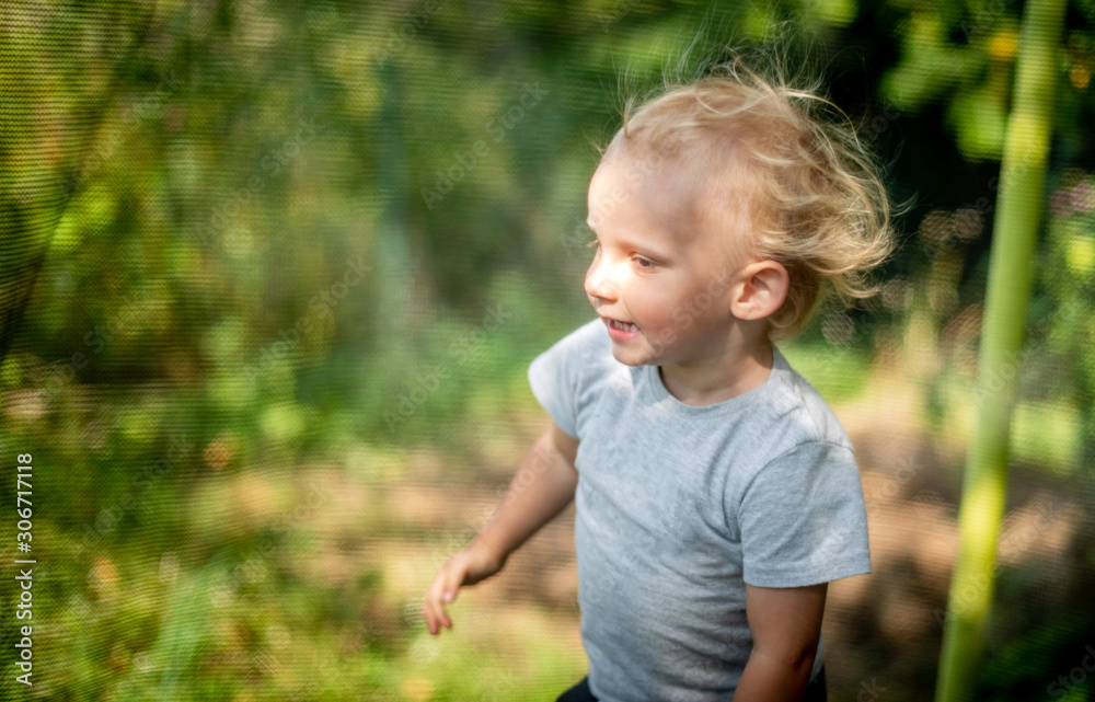 Little child playing and jumping on trampoline outdoor in backyard Little child playing and jumping on trampoline outdoor in backyard