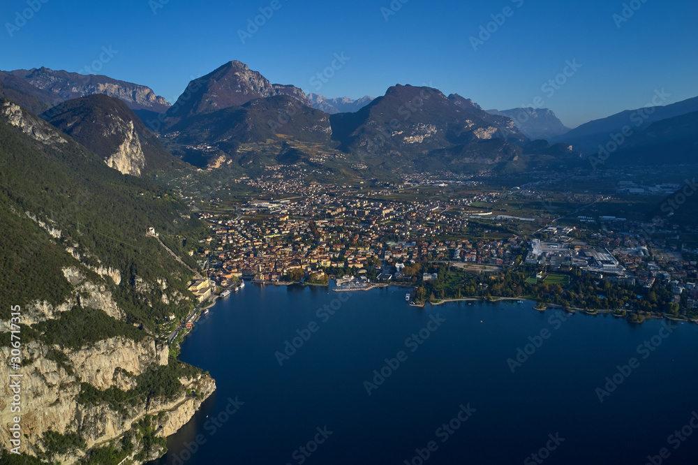 Aerial view of the city of Riva del Garda, Italy. Panoramic view of Lake Garda in the foreground, the city is surrounded by rocks and alpine mountains. Autumn season.