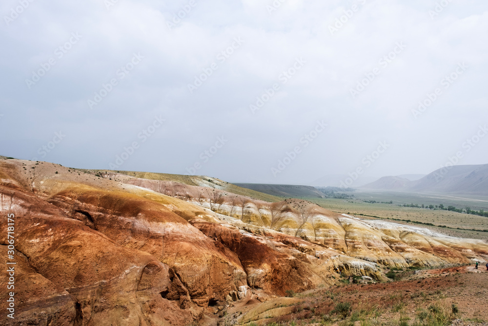 Landscape of an unusual place. Layers of clay, lime, sand. Mars mountains. The color of iron, red shades of the earth. Unusual terrain. Mountain Altai. Tourist trip.