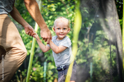 Little child with his dad playing on trampoline outdoor in backyard © leszekglasner
