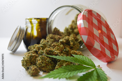 Dry and trimmed cannabis buds stored in a glas jars,a marijuana leave and a big BHO jar. Medical cannabis