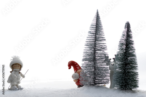 Winter-Stillleben mit Puppen (Skifahrer, Elch und Weihnachtswichtel) im Schnee isoliert auf weißem Hintergrund