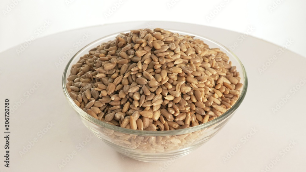 Nuts sunflower rotate are on a table in a plate. Snack in transparent dish on an isolated white background are spinning moving. Delicious and healthy protein-rich diet food. Nuts sunflower rotate are on a table in a plate. Snack in transparent dish on an isolated white background are spinning moving. Delicious and healthy protein-rich diet food.