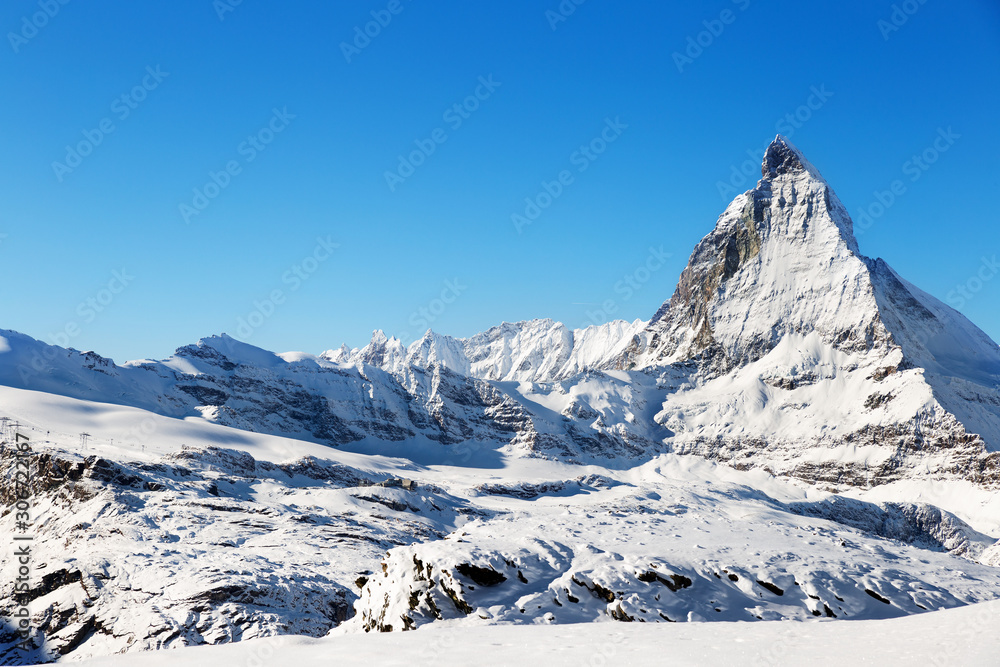 Panorama of the Matterhorn mountain range, covered with fresh snow, and blue sky in the cloudless background. Christmas season, winter and ski slopes on the Swiss Alps.