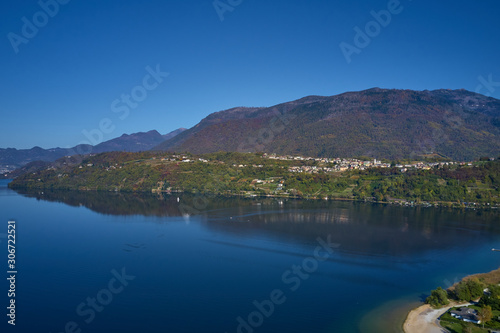 Aerial view of Lake Caldonazzo north of Italy. In the background the trees, Alps, blue sky. Reflection of mountains in water. Autumn season. Multi-colored palette of colors