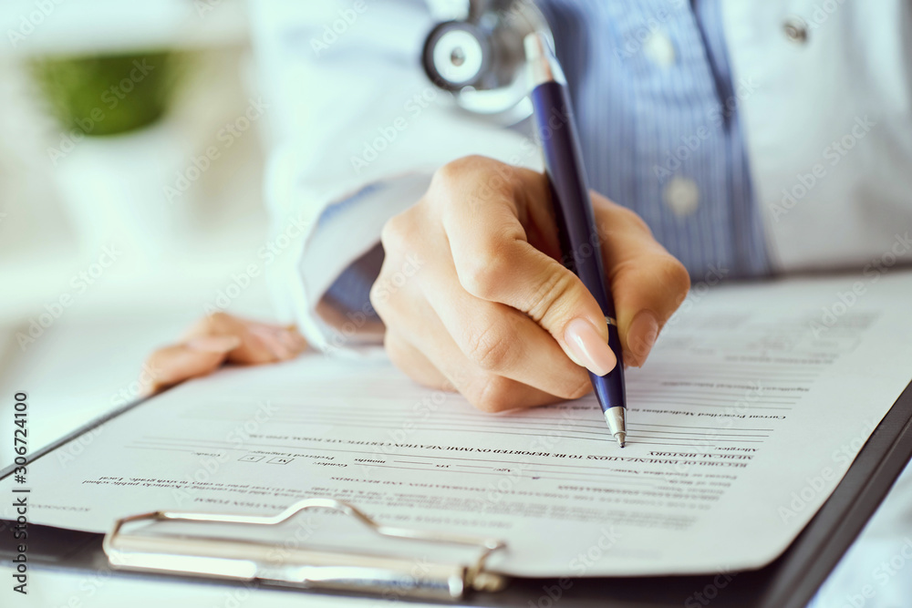 Female doctor hand hold silver pen filling patient history list at clipboard pad. Panacea and life save, prescribing treatment. Female doctor hand hold silver pen filling patient history list at clipboard pad. Panacea and life save, prescribing treatment.