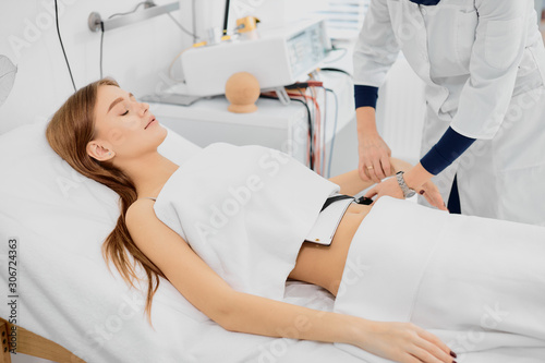 young female lying on bed treating stomach disease, beautiful caucasian woman in hospital