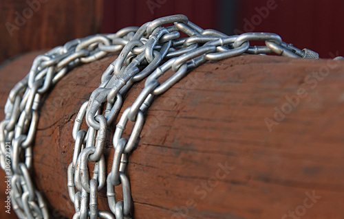 Galvanized metal chain on a brown wooden log