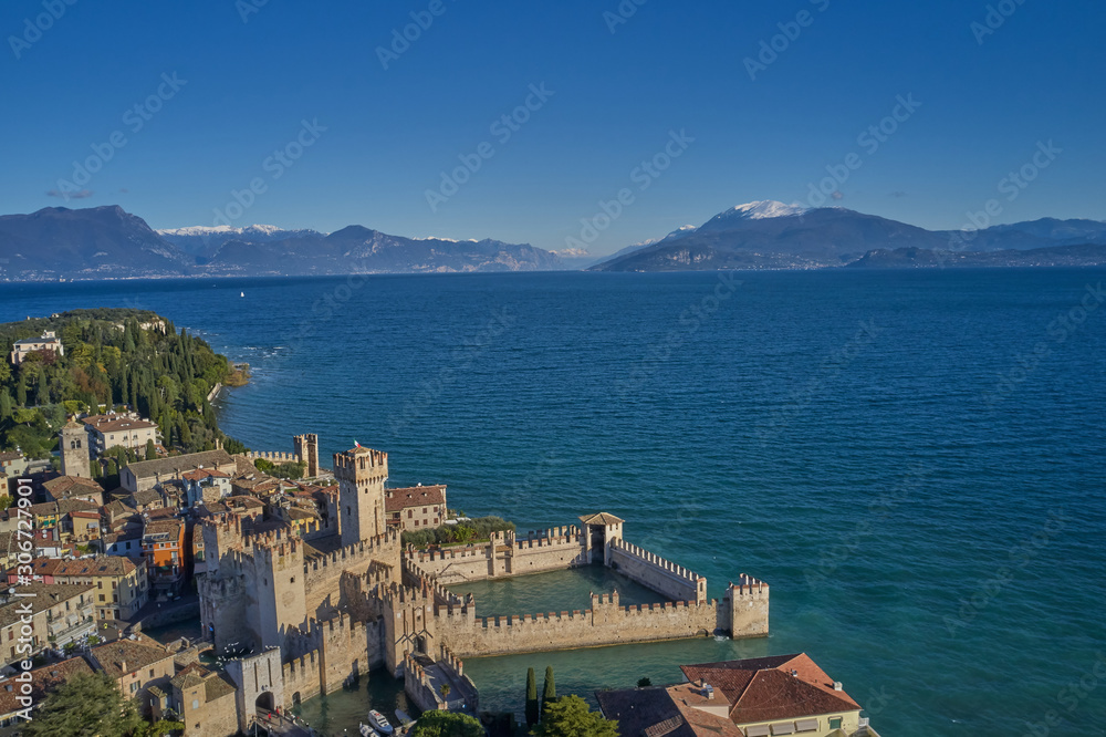 Unique view. Aerial photography, the city of Sirmione on Lake Garda north of Italy. In the background is the Alps in the snow. Resort place. Aerial view. Autumn-winter season