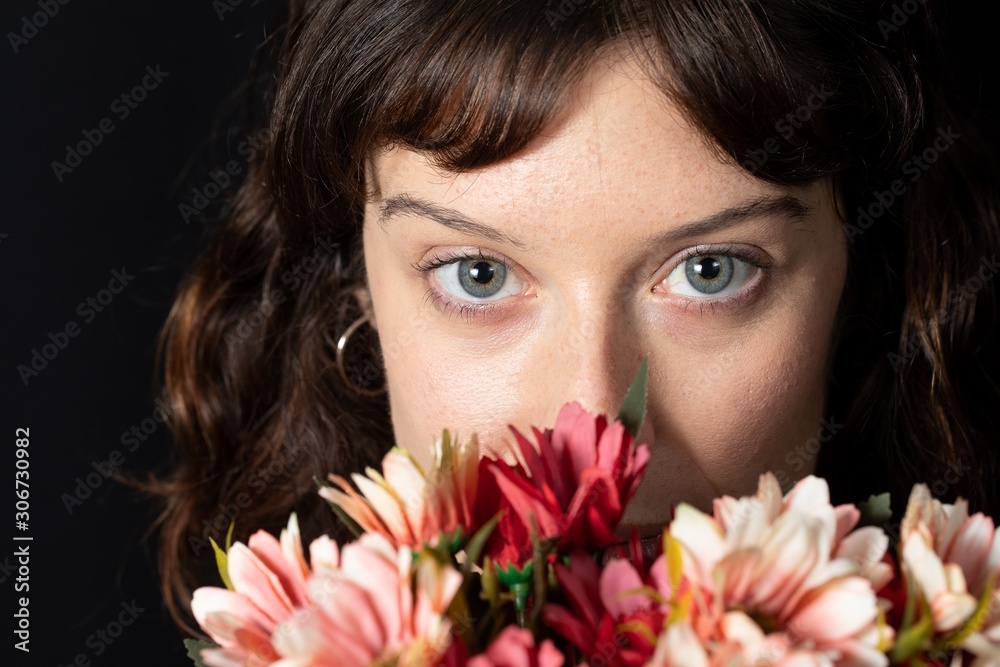 Detail of a girl with brown hair and blue eyes with a bouquet of flowers in front of her face Detail of a girl with brown hair and blue eyes with a bouquet of flowers in front of her face