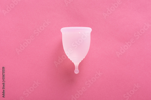 Close up shot of menstrual cup isolated over pink background. Studio picture of modern sanitary products for period. Women health concept, gynecology, hygiene, zero waste alternatives concept. photo