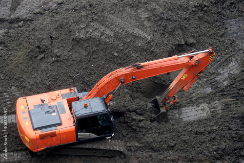 Crawler excavator scoops the earth with a bucket, top view. Earthmoving works, digging on a construction site
