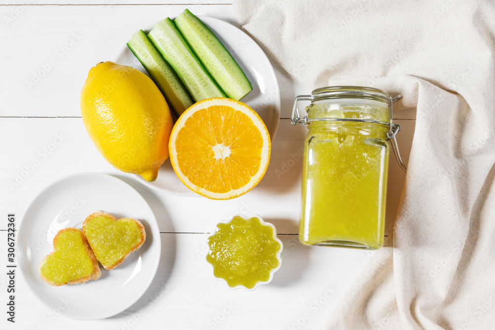 Fototapeta premium Homemade cucumber jam with lemon and heart-shaped toast on a white wooden background.