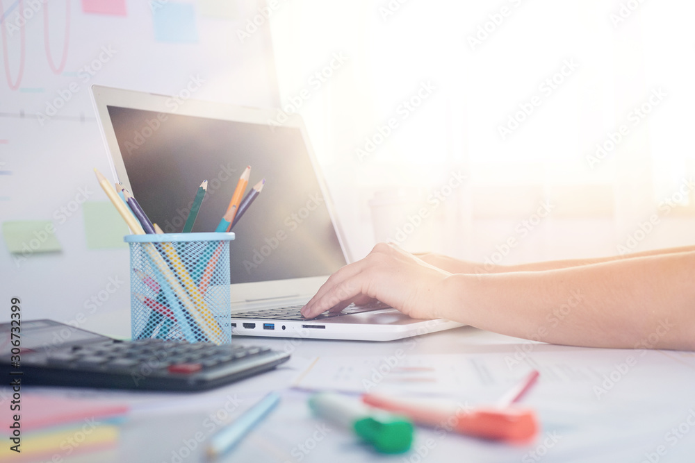 Indoor picture of person working on laptop, having calculator, pencils on table, comfortable working zone, being busy, well lighted room, using modern technologies during work. Technologies concept. Indoor picture of person working on laptop, having calculator, pencils on table, comfortable working zone, being busy, well lighted room, using modern technologies during work. Technologies concept.