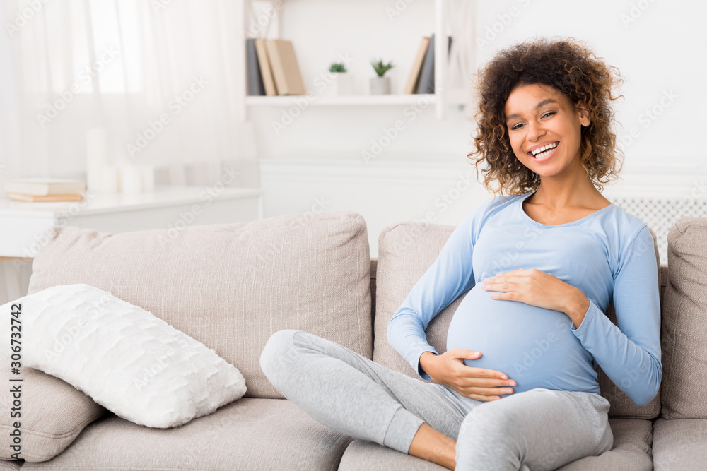 Lovely pregnant woman embracing her belly at home Lovely pregnant woman embracing her belly at home