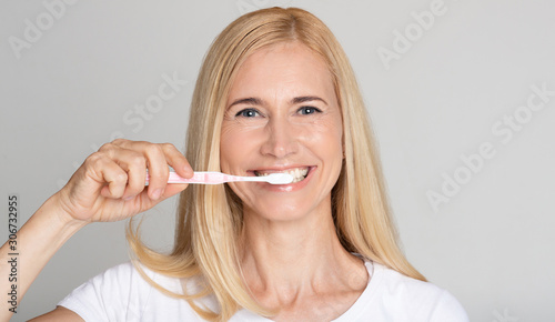 Oral hygiene concept. Middle-aged woman brushing teeth