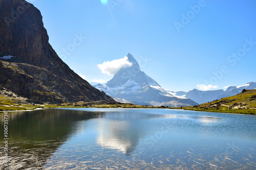 Epic reflection of the Matterhorn (with cloud on its side, and clear blue skies) in the Riffelsee Lake, near the Gornergrat Ridge, Zermatt, Switzerland