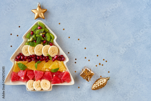 Obraz na plátne Christmas background with fruit salad in fir tree shaped plate and holiday decoration