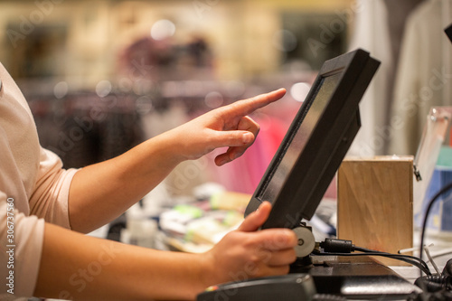 Young woman hands scaning / entering discount / sale on a receipt, touchscreen cash register, market / shop, finance concept, business