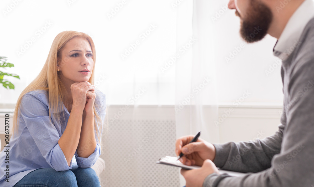 Sad woman talking with male therapist during personal session Sad woman talking with male therapist during personal session