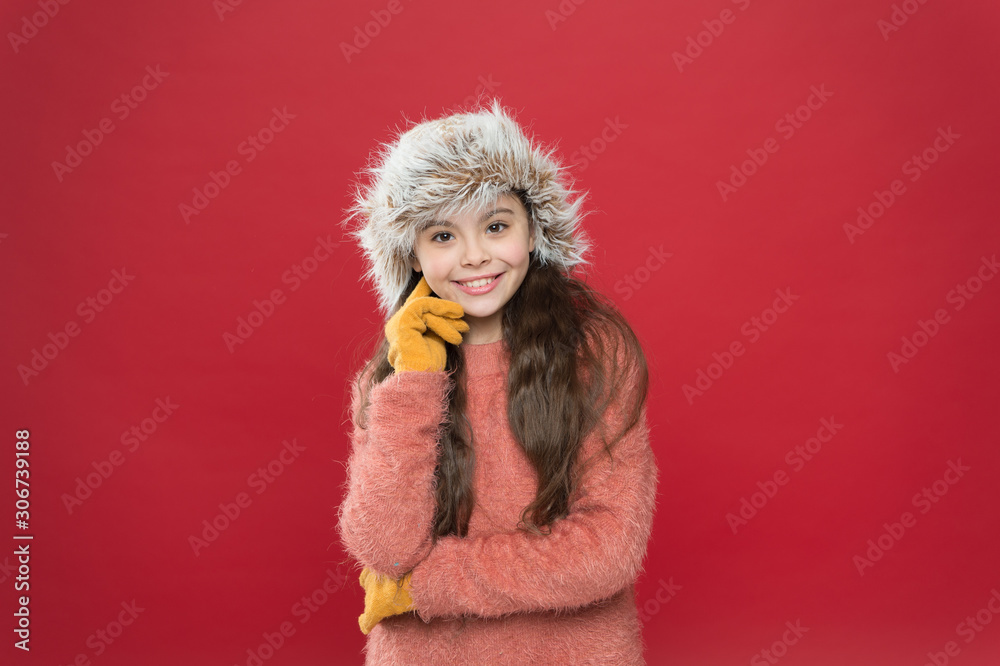 Kid girl smile red background. Soft furry accessory. Winter season. Small fashionista concept. Feeling so cozy. Child long hair soft hat. Winter fashion concept. Warm hat for cold winter weather Kid girl smile red background. Soft furry accessory. Winter season. Small fashionista concept. Feeling so cozy. Child long hair soft hat. Winter fashion concept. Warm hat for cold winter weather