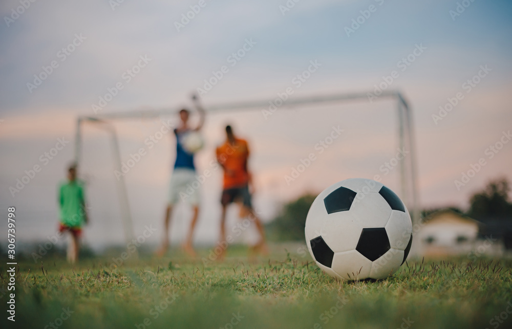 Obraz premium Silhouette action sport outdoors of diversity of kids having fun playing soccer football for exercise in community rural area under the twilight sunset sky.