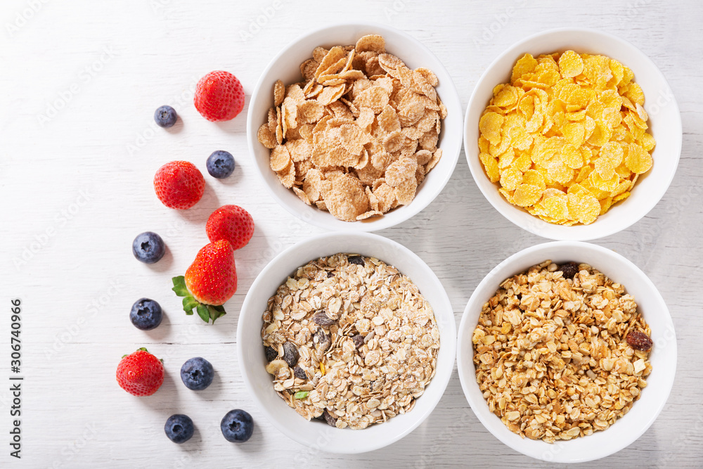 bowls of cereals, granola, corn flakes and fresh berries for breakfast, top view bowls of cereals, granola, corn flakes and fresh berries for breakfast, top view