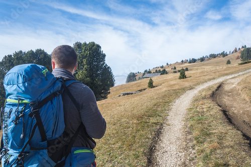 Male hiker with backpack enjoying autumn view on sunny midday, Dolomites Italy