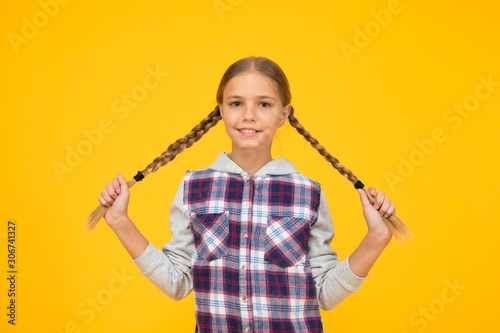 Kid long hair. Small girl checkered shirt. Happy international childrens day. Little girl yellow background. Good mood concept. Positive vibes. Sincere emotions. Having fun. Cute braided girl