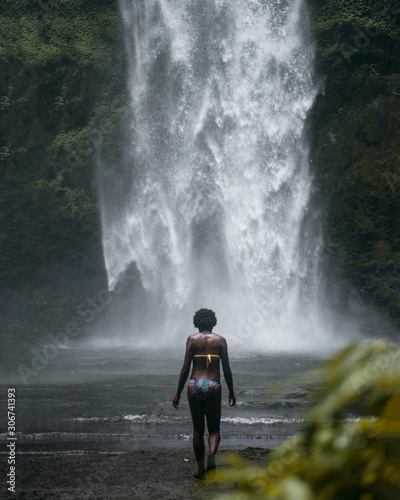 chica afro observando cascada tropical