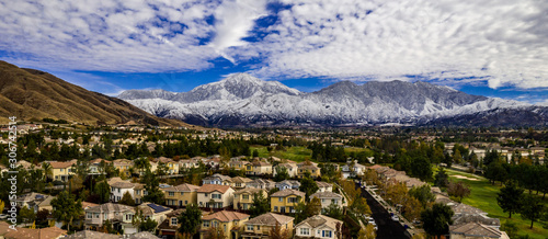 Aerial panorama of snow covered San Gorgonio and Little San Bernardino Mountains on a winter day above Yucaipa Valley with blue sky, white clouds, houses, hills © joel